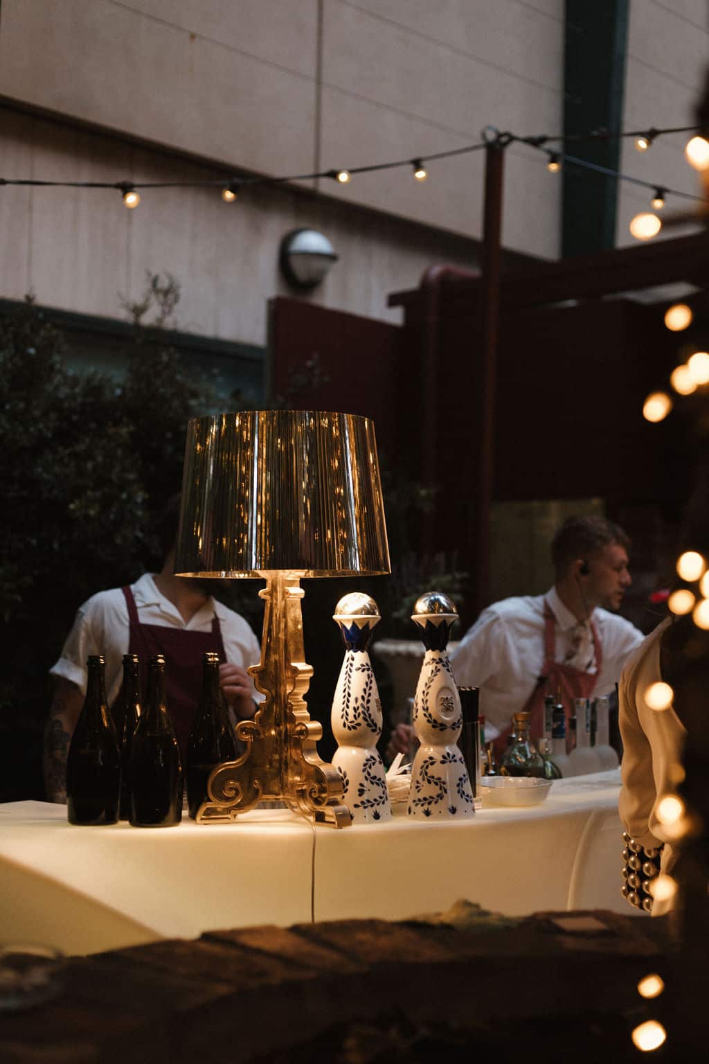 Bartenders at an outdoor event bar at Pepe's, under festoon lights