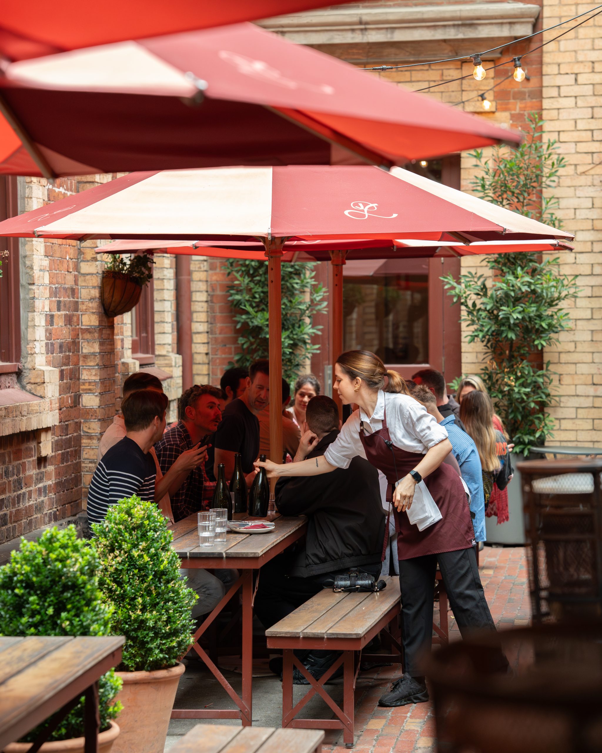 A waiter serving a table under red umbrellas in Pepe's courtyard