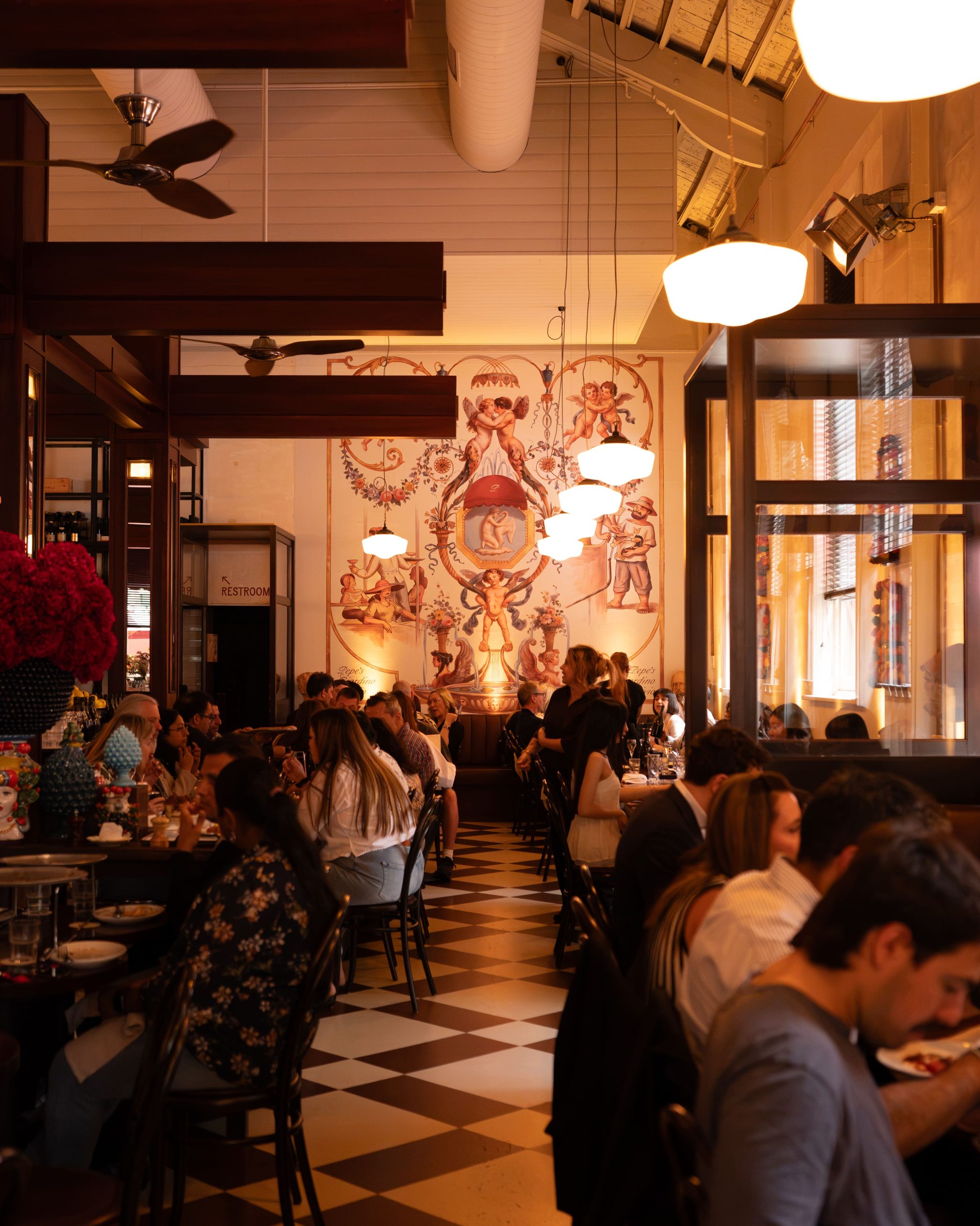 A busy evening in Pepe's Main Dining Room, beneath the painted mural with a checkerboard floor